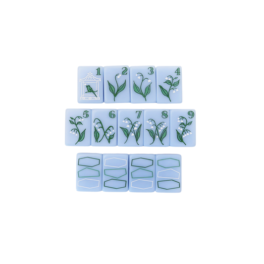 Kayce Hughes mahjong tiles close-up: bam suit 1 through 9 with lily of the valley botanical artwork on soft blue acrylic, with dragon tiles below