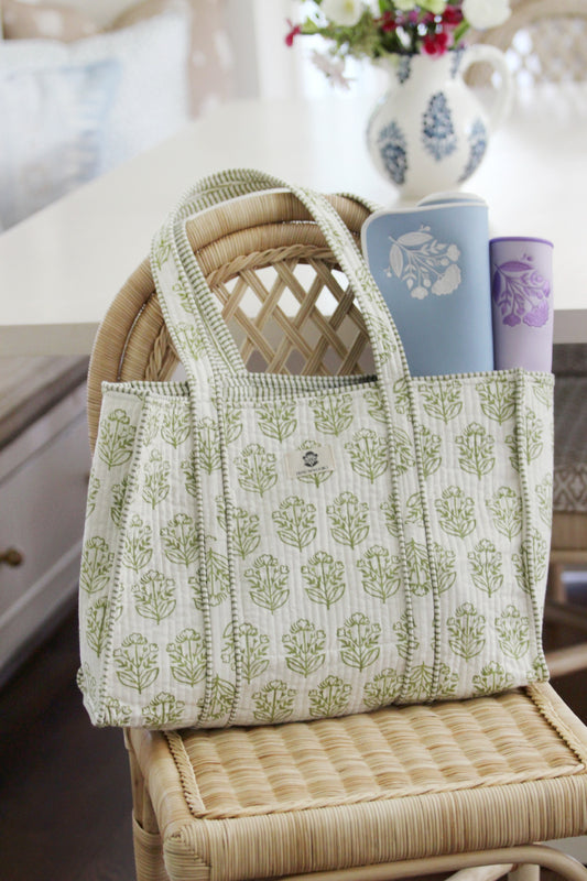 Pistachio block-print mahjong tote on a rattan chair holding rolled blue and lavender mats