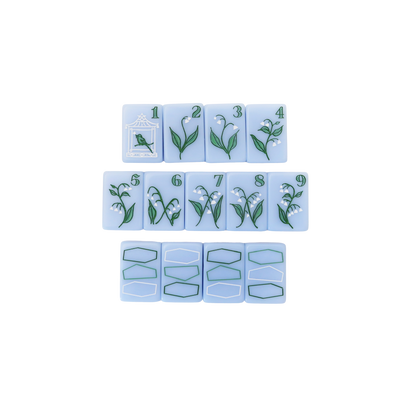 Kayce Hughes mahjong tiles close-up: bam suit 1 through 9 with lily of the valley botanical artwork on soft blue acrylic, with dragon tiles below