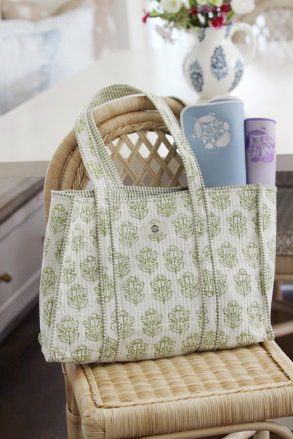 Pistachio block-print mahjong tote on a rattan chair holding rolled blue and lavender mats