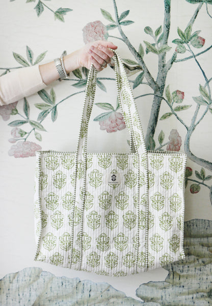 Pistachio block-print quilted mahjong tote held up against floral wallpaper